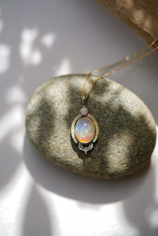 Opal pendant necklace on a stone surface with soft lighting