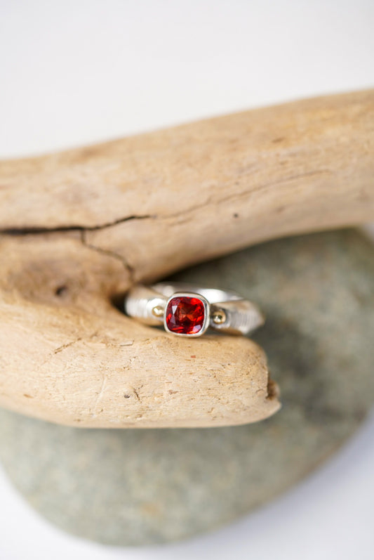 Bright red sunstone silver ring next to a piece of driftwood