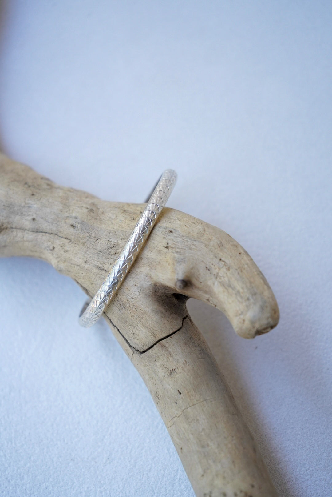 a silver bracelet on driftwood