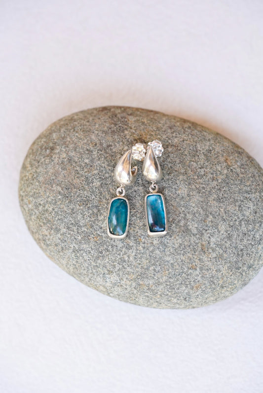 Pair of silver earrings with dark blue stones on a stone surface