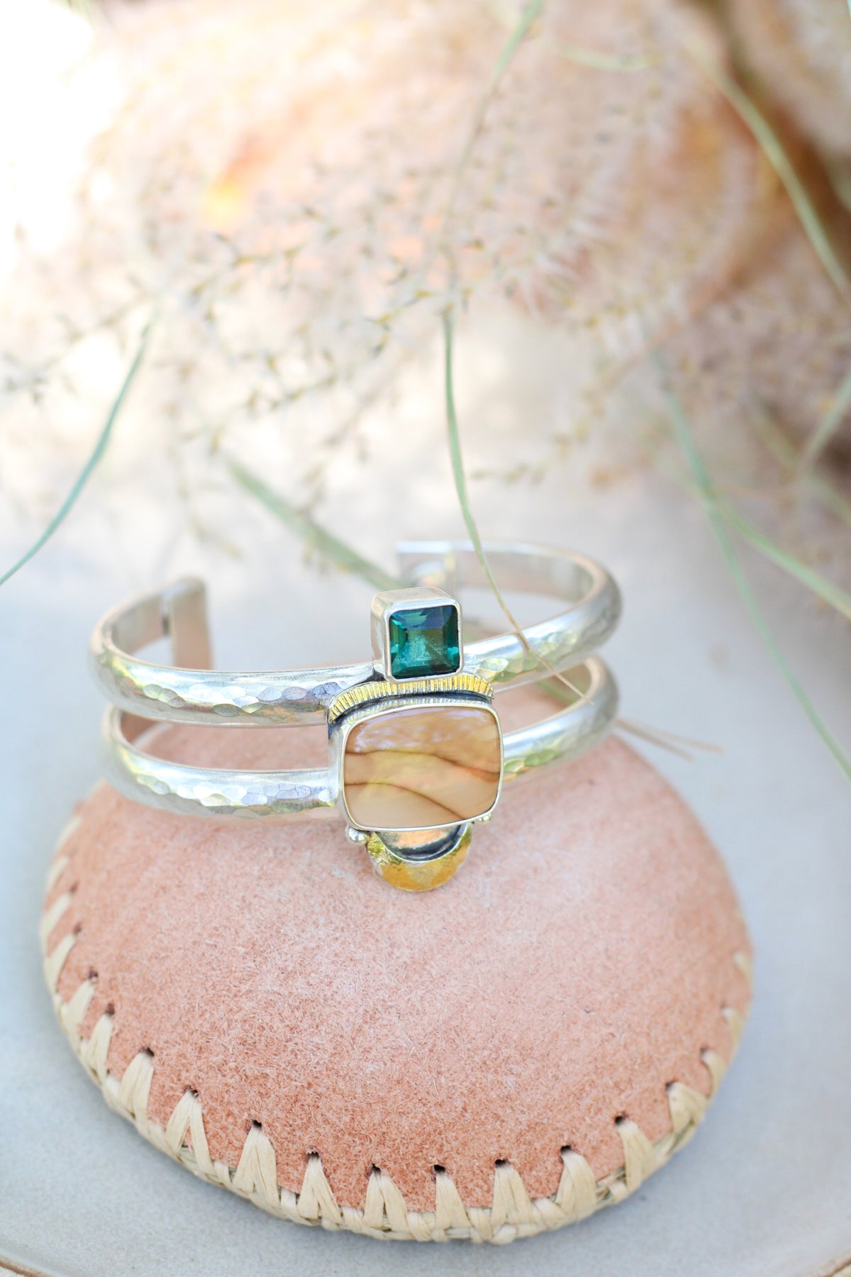 Statement cuff with brown and green stone on a pink leather bowl