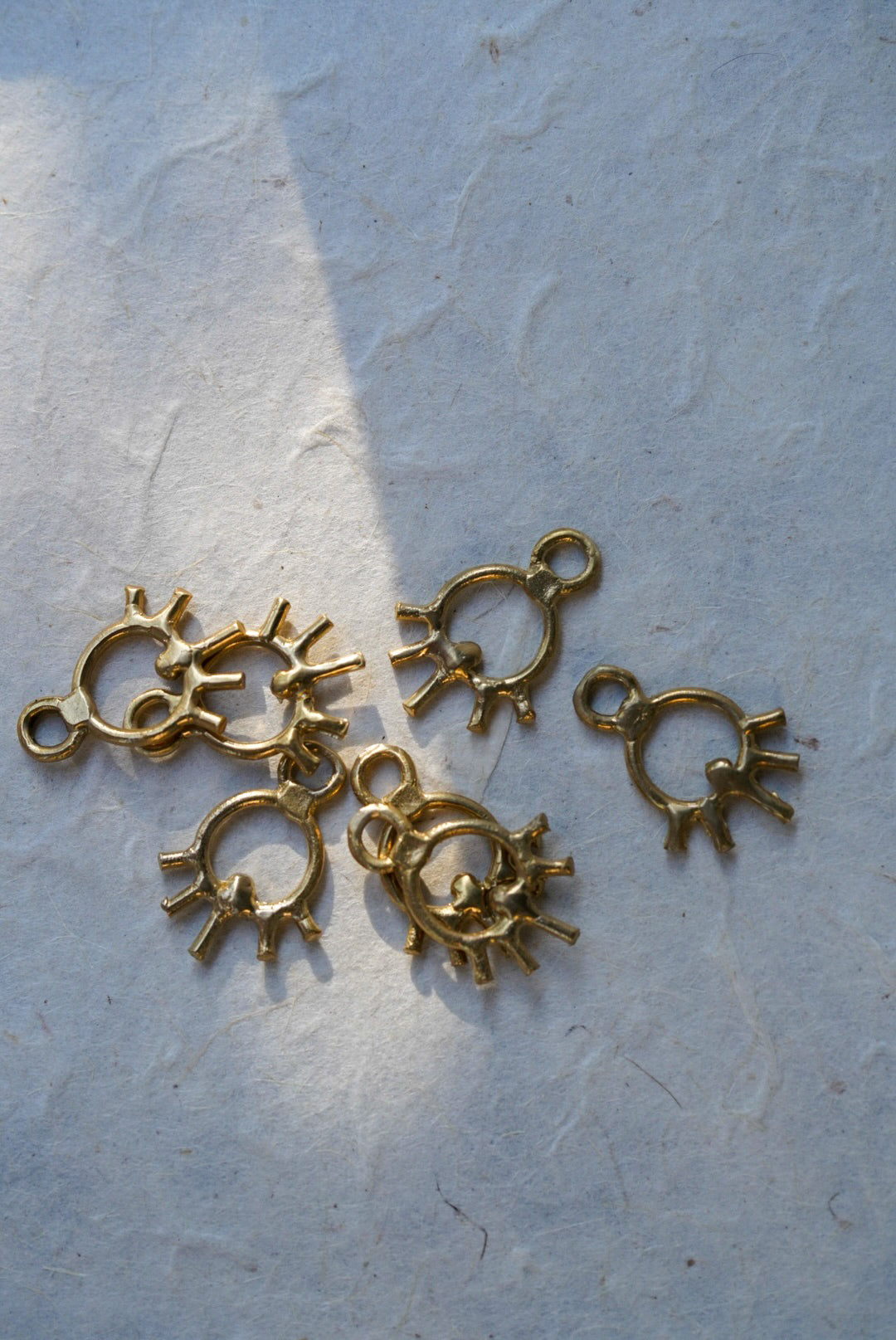 Five small bronze sun charms arranged on a light textured surface.
