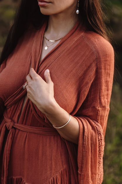 a women in a orange dress, wearing gold jewelry 