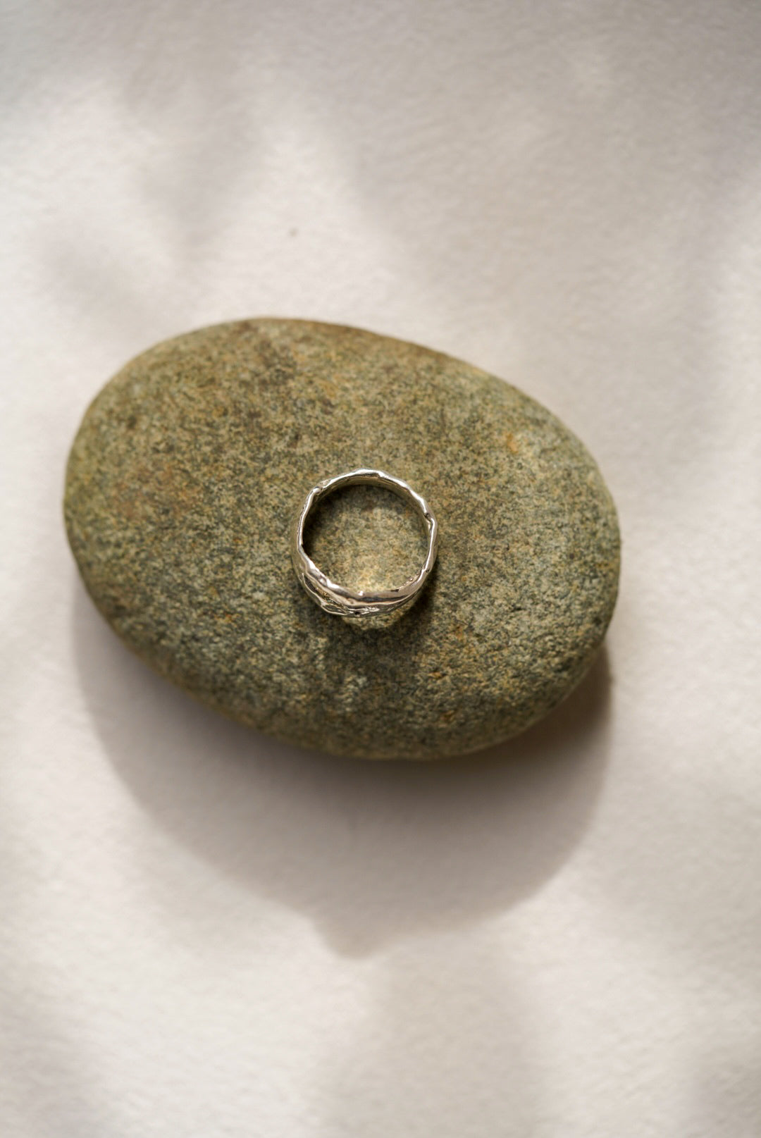 Silver ring on a textured stone against a neutral background