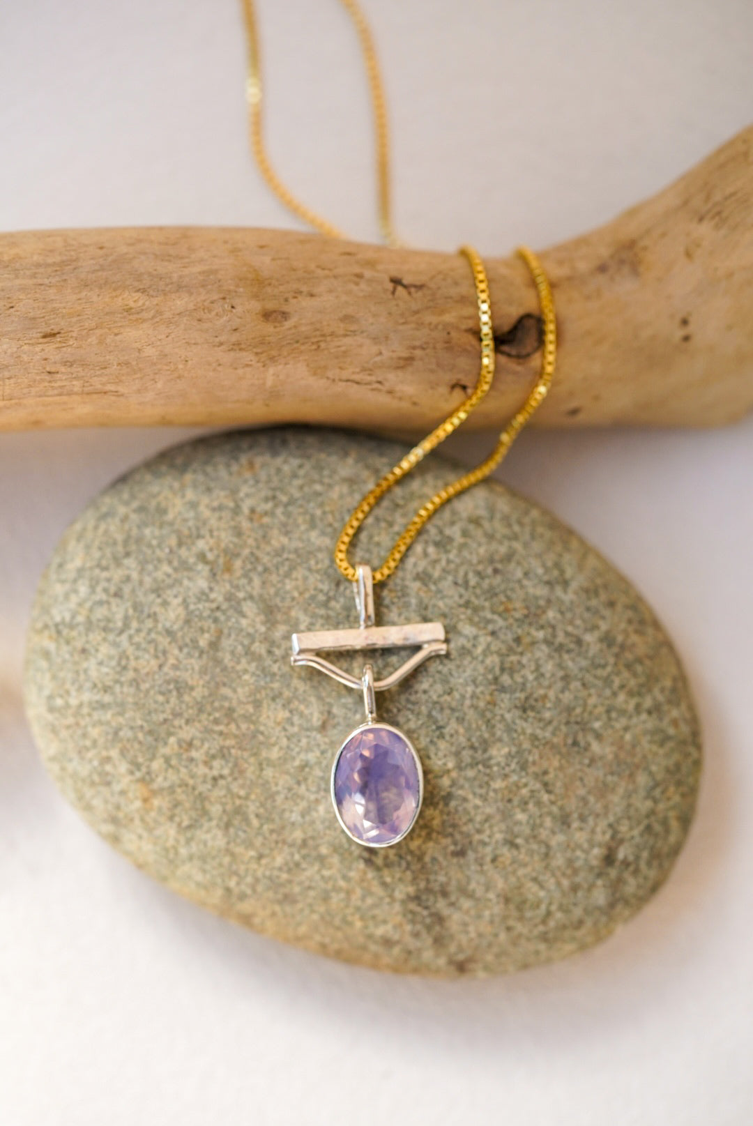 Necklace with a purple pendant on a stone surface