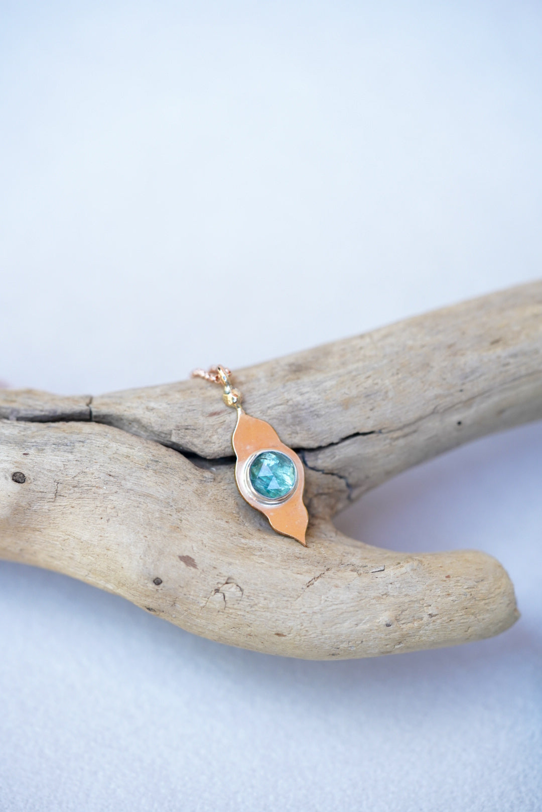 Green pendant with gold temple design on a piece of driftwood 