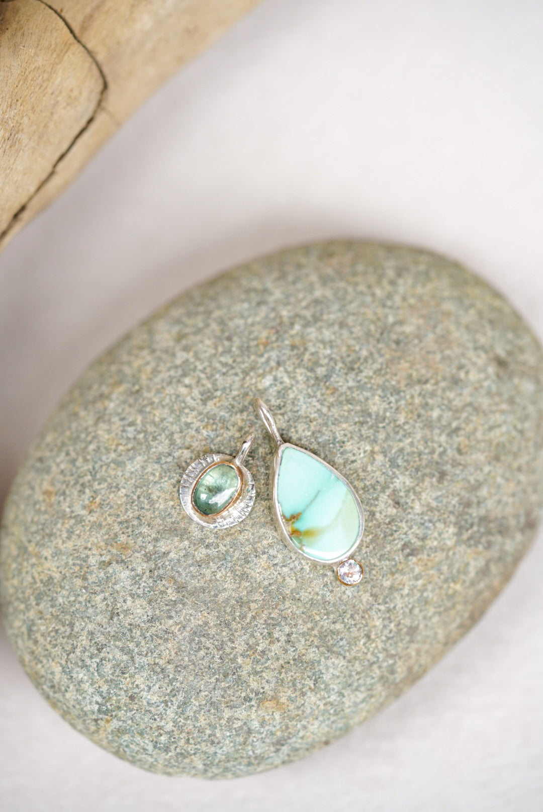 Two pendants with a variscite stone and green kyanite on a stone surface