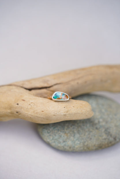 Ring with a colorful stone on a piece of driftwood