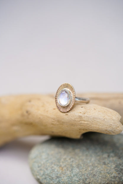 Moonstone ring on top of a piece of driftwood with a white background