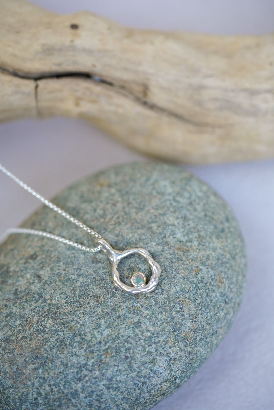 Silver necklace with a circular pendant on a stone surface
