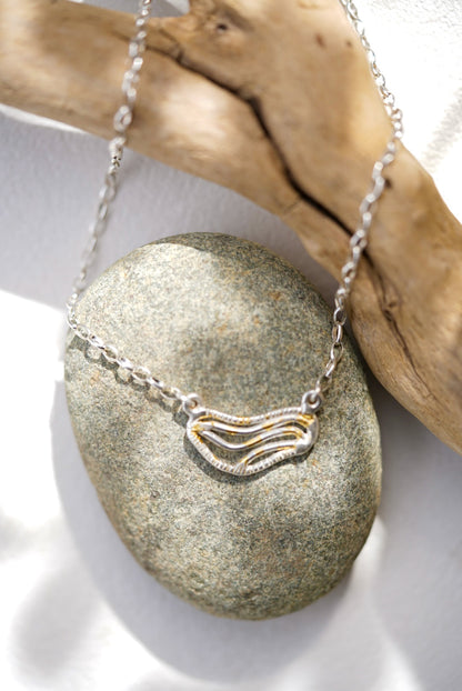 Silver necklace with a pendant on a stone surface