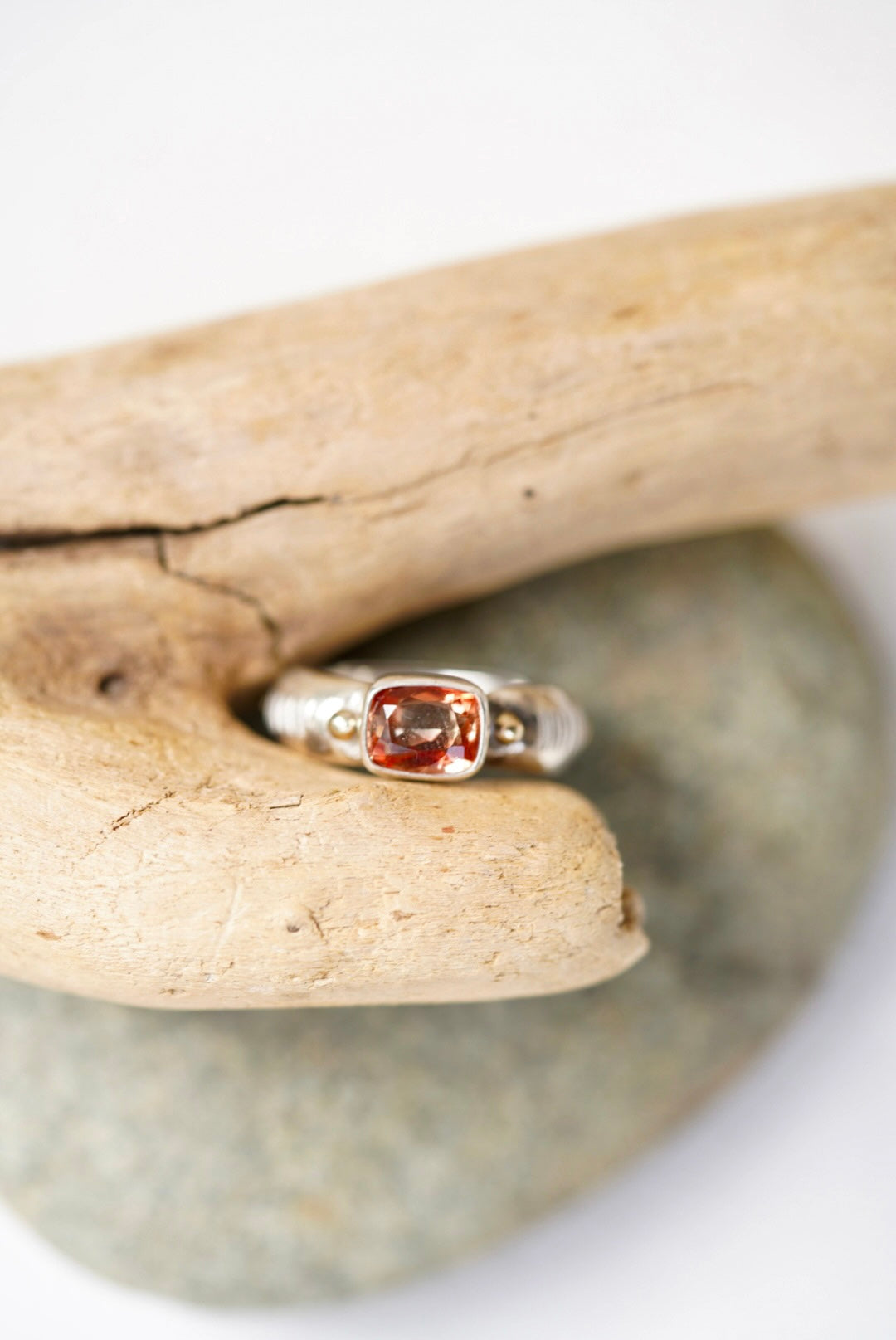 Sunstone silver ring next to a piece of driftwood