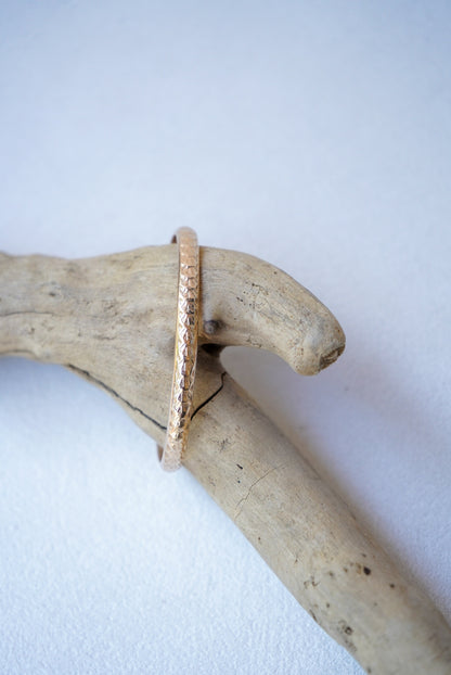 a gold bracelet on driftwood