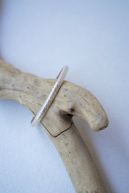 a silver bracelet on driftwood
