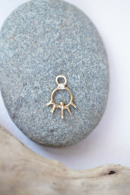 sun charm in bronze on a rock