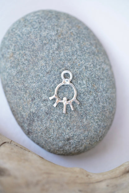 sun charm in silver on a rock