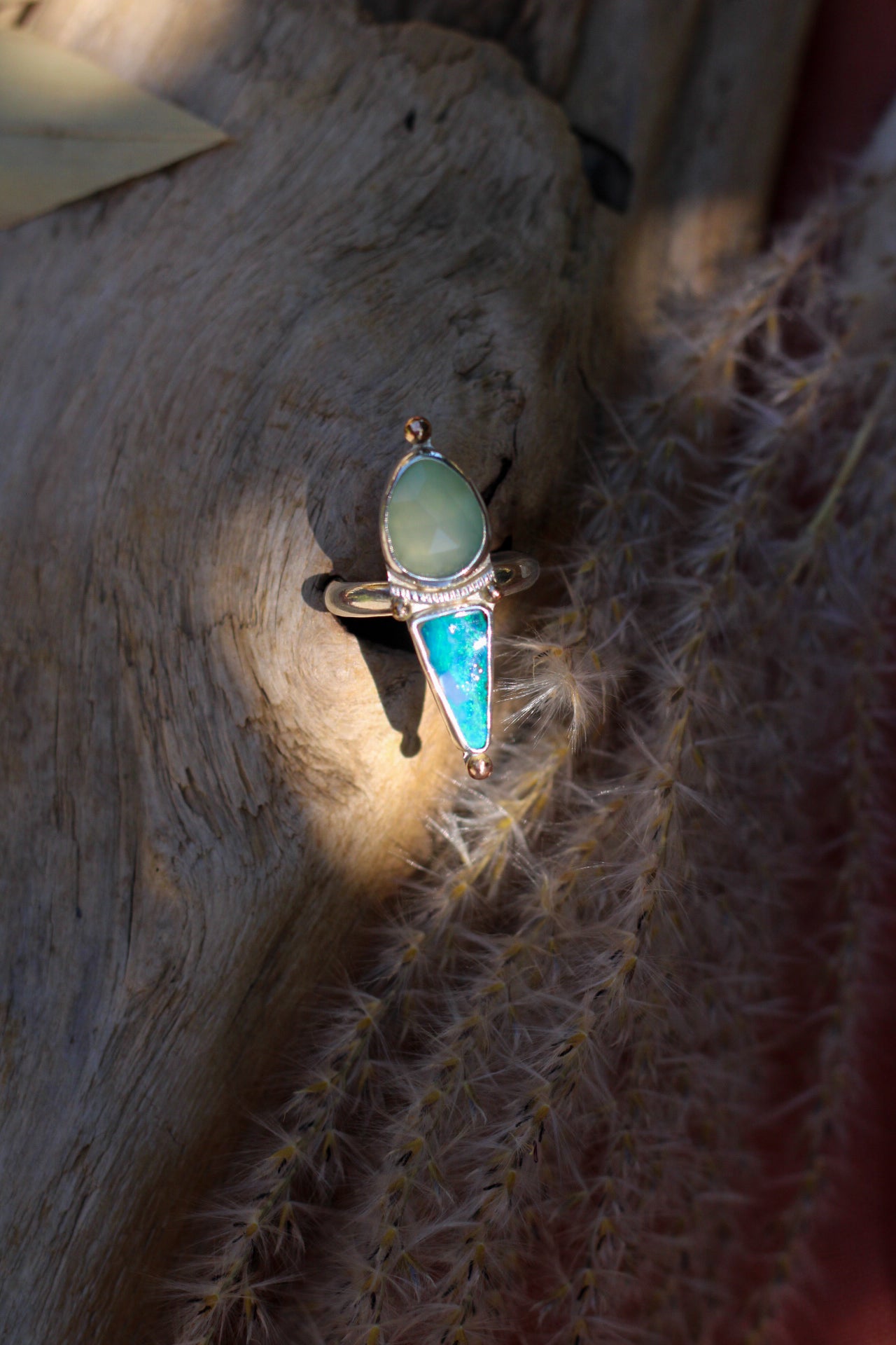 Ring with chalcedony and opal stones on a piece of driftwood