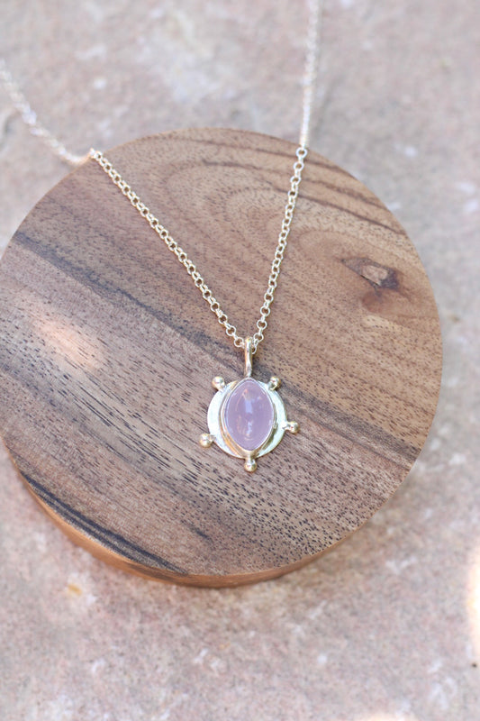 Necklace with a purple chalcedony pendant on a wooden coaster