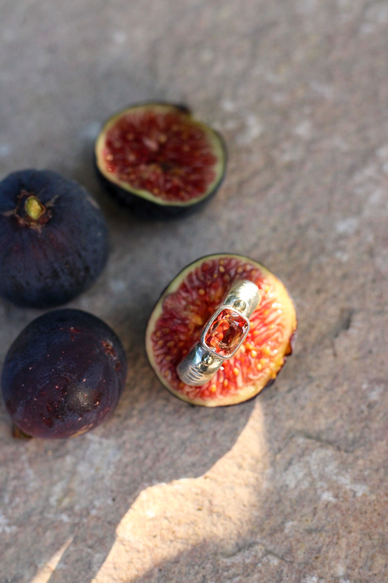 Figs on a stone surface with one fig containing a ring.