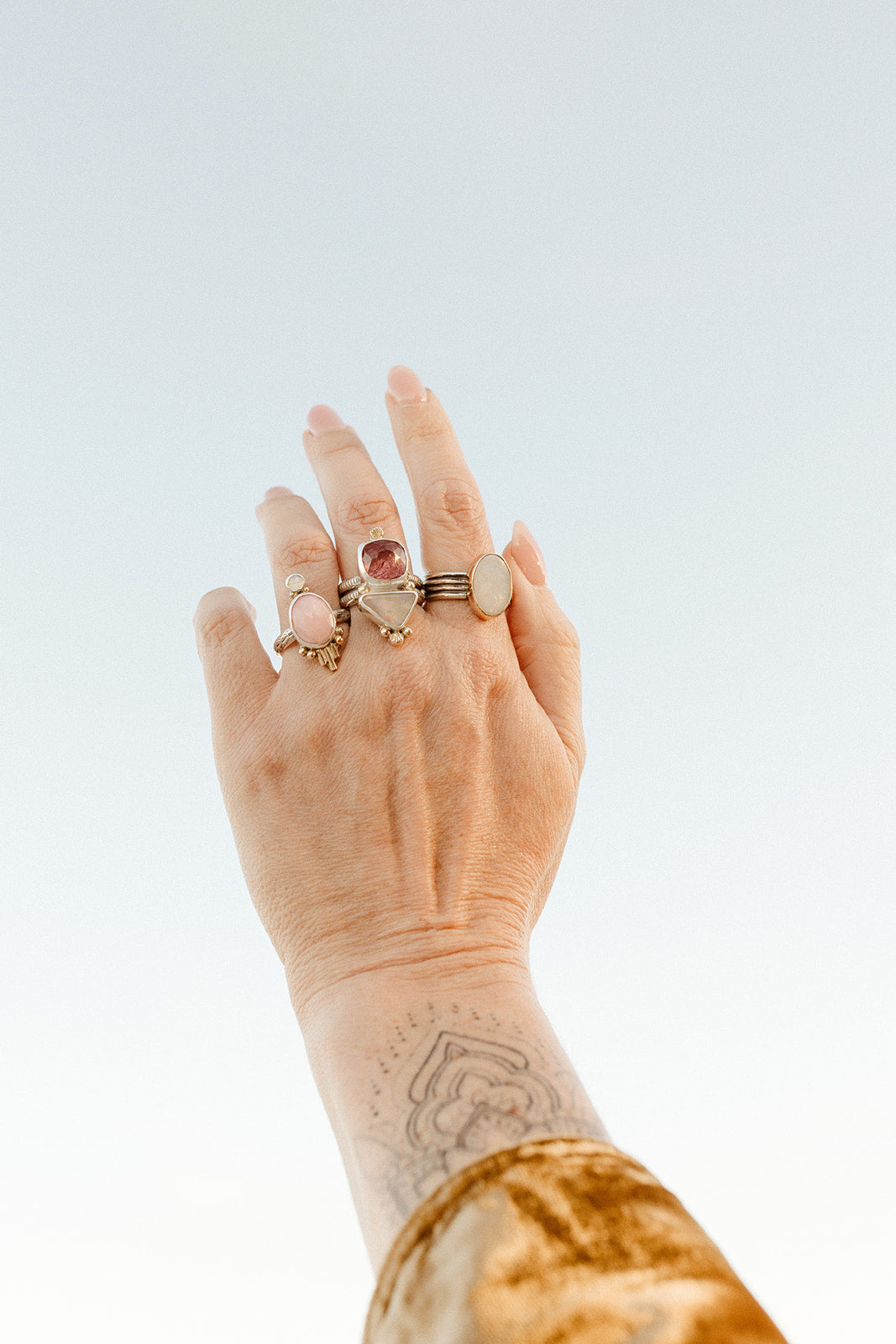 A hand reaching for the sky wearing three statement rings.