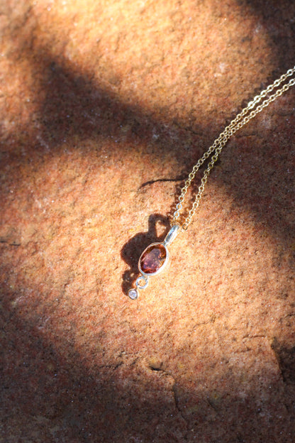 Necklace with a tourmaline and diamond pendant  on a textured surface