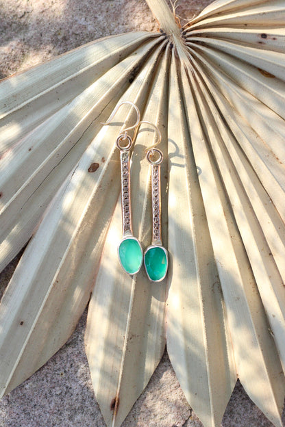 Green earrings on a palm leaf