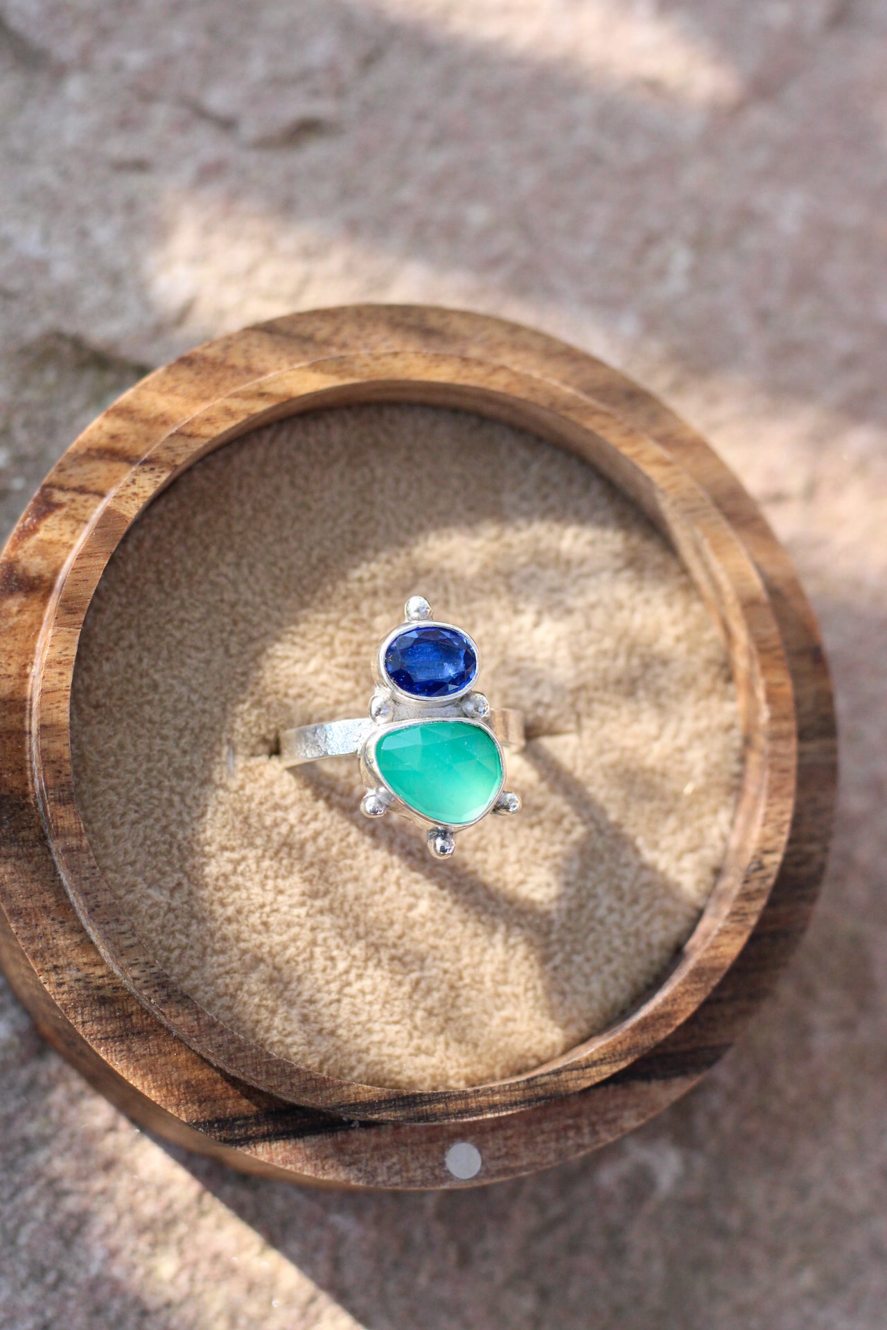 cobalt blue kyanite and green chalcedony ring on a wood ring box on a neutral background