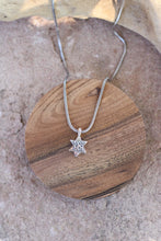 Load image into Gallery viewer, Silver star-shaped pendant necklace on a wooden surface
