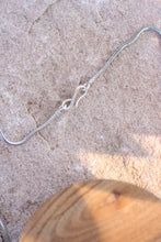 Load image into Gallery viewer, Silver chain clasp on a textured surface with a wooden object in the foreground
