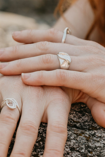 Close-up of two hands with silver rings on a natural background