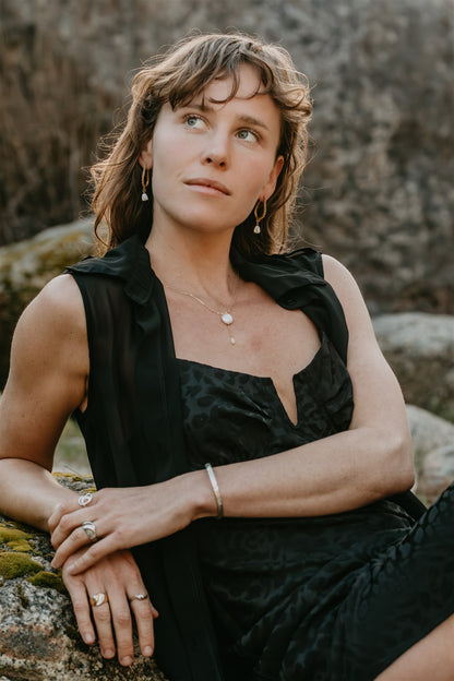 Woman in a black dress sitting on a rock with a natural background